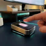 Fingerabdruckscanner mit rosa LED-Beleuchtung auf dunklem Schreibtisch, Finger nähert sich dem Gerät