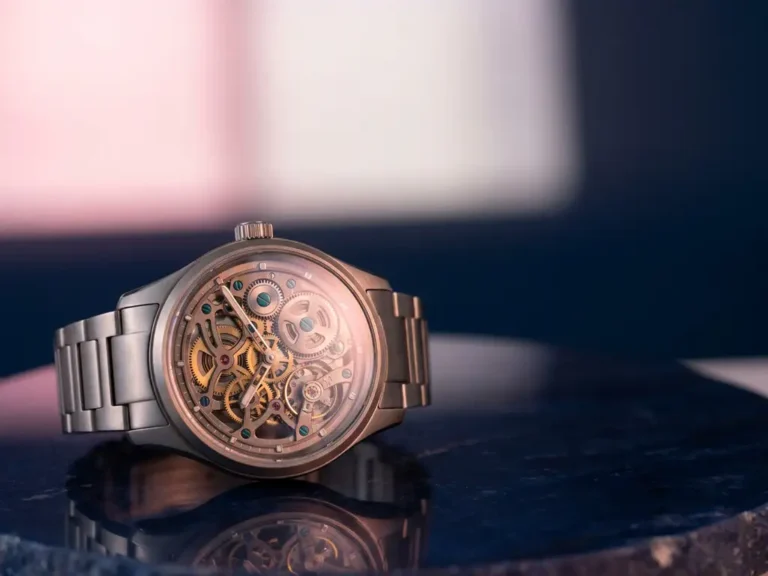 Moderne Armbanduhr mit sichtbaren Zahnrädern auf dunkelblauer Oberfläche, rosa Beleuchtung und türkise Akzente