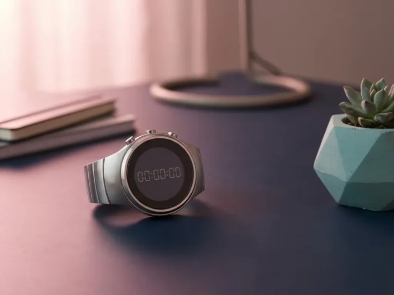 Silberne Stoppuhr auf dunklem Schreibtisch neben Sukkulente, rosa Beleuchtung mit geometrischen Schatten