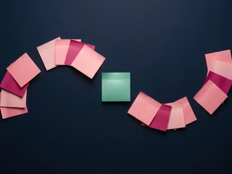 Farbige Haftnotizen in Rosa, Magenta und Türkis in geschwungenem Muster auf dunkelblauem Untergrund, Draufsicht.
