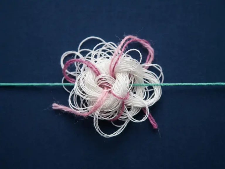 Weißes Fadenbündel mit Knoten, durchzogen von rosa und magentafarbenen Fasern, neben einem geraden türkisen Faden auf dunkelblauem Untergrund.